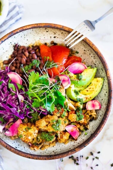 烟熏花椰菜辣椒碗！ These filling vegan bowls are full of flavor and loaded up with healthy veggies. Served over seasoned black beans (and optional rice) with Mexican Slaw, radishes, avocado, cilantro and pickled onions. #roastedcauliflower #bowls #veganbowls #veganrecipes #buddhabowls #chimichurri #eatclean #cleaneating #plantbased #healthybowls